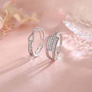 Close-up detail of geometric silver open rings with intricate knot and row stone designs