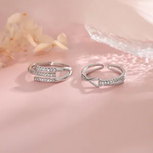 Close-up of elegant silver-tone geometric open rings with sparkling pavé stones on pink background