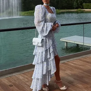 Elegant woman wearing a blue floral ruffled dress standing on a wooden deck by a lake