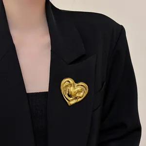Detailed close-up view of a stylish gold heart-shaped metal brooch on a black blazer lapel.