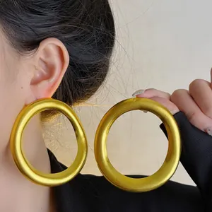 Close-up detail of exaggerated oversized golden hoop earrings with vintage texture