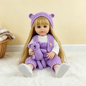Realistic reborn baby doll in purple knitted clothes holding a small matching bear