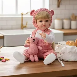 Detailed shot of a lifelike reborn baby doll in pink knitted outfit with teddy bear