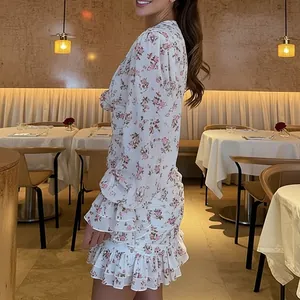 Robe à fleurs blanche élégante avec col en V et volants dans un chic restaurant