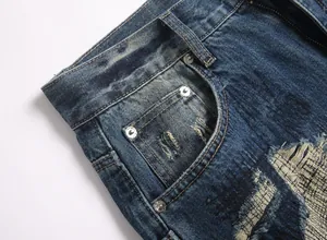 Close-up detail of distressed denim jeans with ripped patches and punk style embroidery