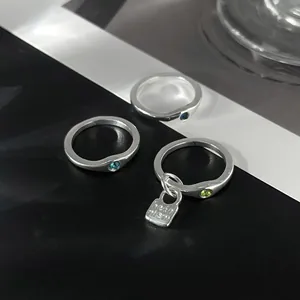 Detail of irregular pleated alloy rings with colorful zircon stones and tag.
