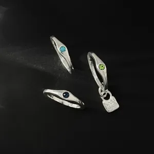 Detailed macro view of silver-toned irregular wrinkled rings with colorful gemstones.