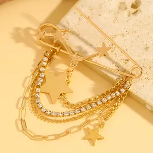 Detailed macro view of a gold safety pin brooch with tassel chains and star charms.