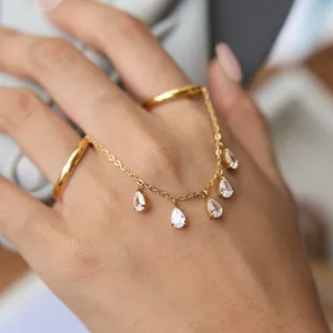 Bague multi-doigts en acier inoxydable doré avec pampilles en zircon sur la main