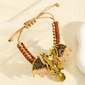 Macro-opname van een geweven armband met een gedetailleerde gouden vliegende draak hanger