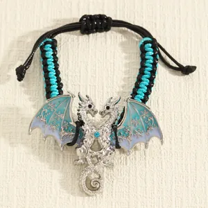 Gedetailleerd zicht van zilveren drakenarmband met blauwe emaille vleugels en zwart koord.