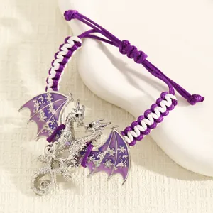 Gedetailleerde close-up van zilveren drakenarmband met paarse emaille vleugels en koord