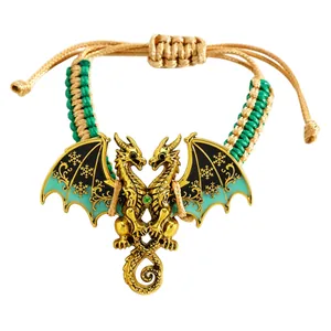 Detail van vintage gouden draakarmband met turquoise emaille vleugels en gevlochten koord.