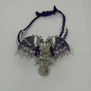 Detailopname van zilveren dubbele draak bedel met paars emaille op de geweven armband.
