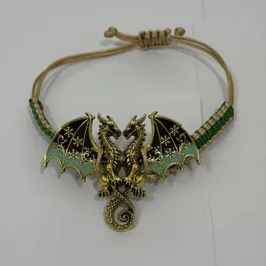 Detailopname van een drakenarmband met groene emaille vleugels en vlechtwerk