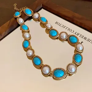 Vintage gold-tone necklace with oval turquoise and pearl stones displayed on a mirror.