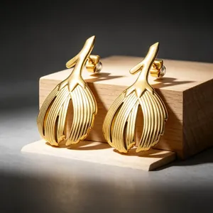 Macro detail of vintage gold stainless steel leaf earrings on a wooden display block