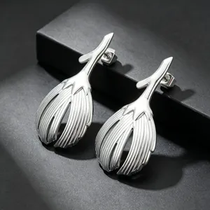 Close-up of silver leaf earrings showing metallic texture and detailed vertical grooves.