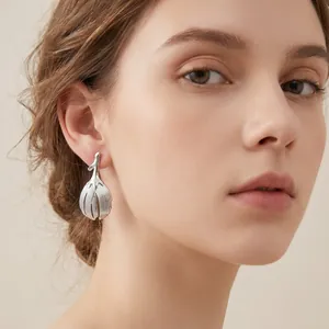 Detailed close-up of a retro leaf stainless steel earring elegantly worn by a model