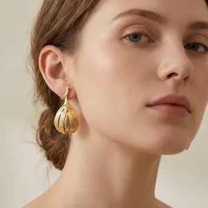 Detailed close-up showing a vintage golden leaf stainless steel earring on a female model
