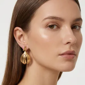 Close-up shot of elegant gold ribbed bud-shaped stainless steel earrings on a model