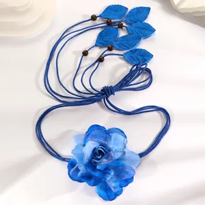 Detailed view of bohemian blue woven waist rope with fabric flower and leaf charms