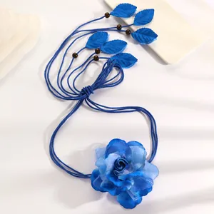 Detailed view of handcrafted blue fabric rose and leaf charms on ethnic woven waist chain
