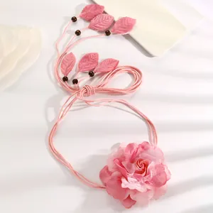 Detailed view of the elegant pink fabric rose and leaves on a bohemian woven waist chain.