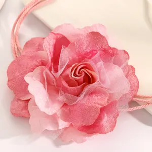 Macro view of a large layered pink fabric flower on a bohemian braided rope waist belt