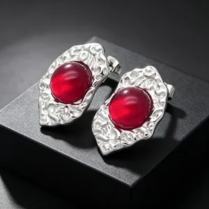 High-detail macro view of vintage irregular silver stud earrings with a translucent red stone