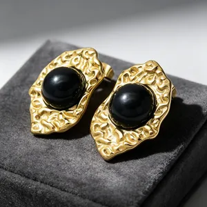 Close-up of French vintage 18K gold-plated earrings with black stones and hammered texture