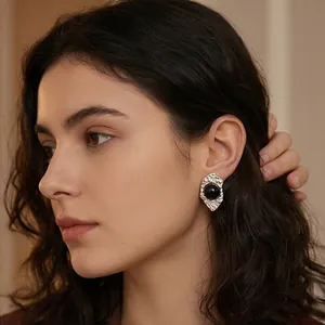 Close-up of vintage irregular metal earrings with black cat's eye stone worn by a model