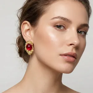 Detail shot of model wearing French vintage irregular gold earrings with a red cat's eye stone