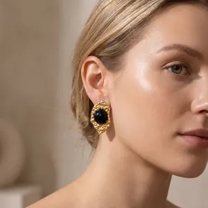 Elegant gold-plated geometric earring with black stone detail worn by a female model