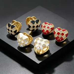 Close-up of heart-shaped checkered earrings with rhinestones in black, red, and white.