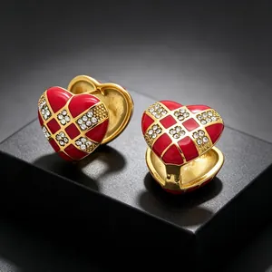Detailed close-up of red enamel heart-shaped earrings featuring gold checkerboard pattern