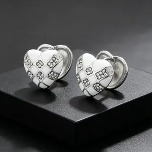Close-up detail of heart earrings featuring white enamel lattice design and small crystals