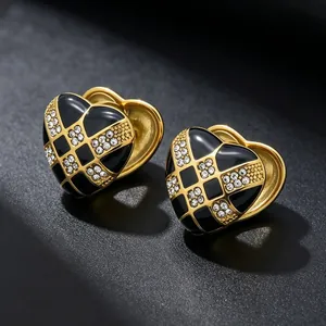 Macro view of gold-toned heart earrings with black checkerboard enamel and rhinestones