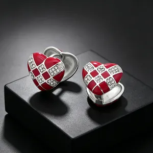 Close-up of elegant red enamel heart earrings featuring checkered rhinestone inlay