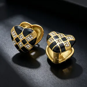 Close-up of checkerboard heart earrings with sparkling rhinestones in gold and black.