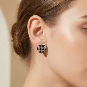 Close-up of heart-shaped checkerboard earrings with rhinestones on model's ear