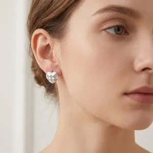 Close-up view of elegant heart-shaped checkerboard earrings with pavé crystals on a model.