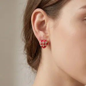 Detailed close-up showing a red checkerboard heart stud earring with rhinestones on an ear