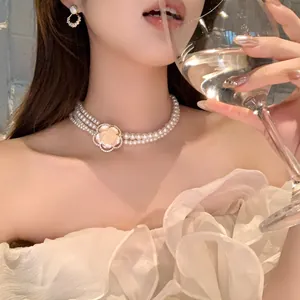 Gros plan d'un collier de perles élégant à plusieurs rangs avec pendentif fleur rose