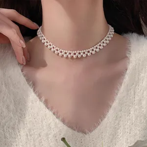 Détail d'un élégant collier ras-du-cou en perles tissées à deux rangs avec un pull blanc