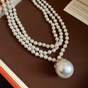 Détail du collier de perles à trois rangs avec grand pendentif perle à dentelle.
