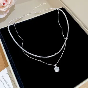 Vue détaillée d'un élégant collier de perles à deux rangs avec pendentif en cristal carré
