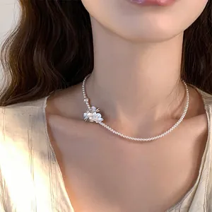 Gros plan d'un élégant collier ras du cou en perles avec pendentifs fleurs blanches délicats