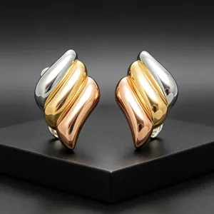 Close-up of tri-color angel wing earrings featuring gold, silver, and rose gold plating