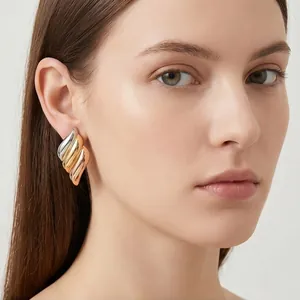 Close-up detail of 18K gold plated tricolor ribbed angel wing earrings on model